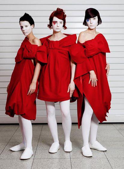 3 women in red dresses and white painted faces